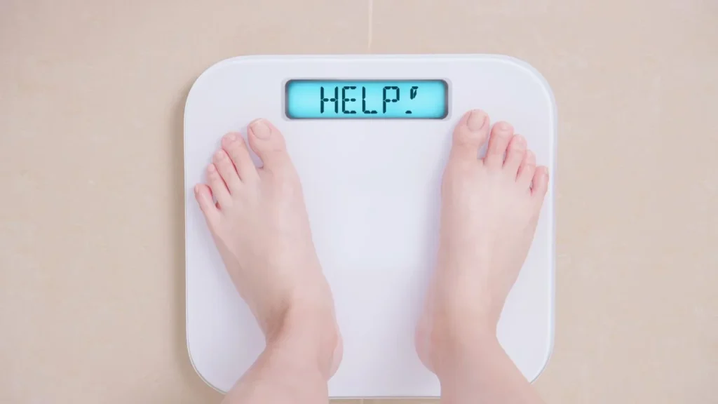 Person standing on a scale with a display that reads "Help!"